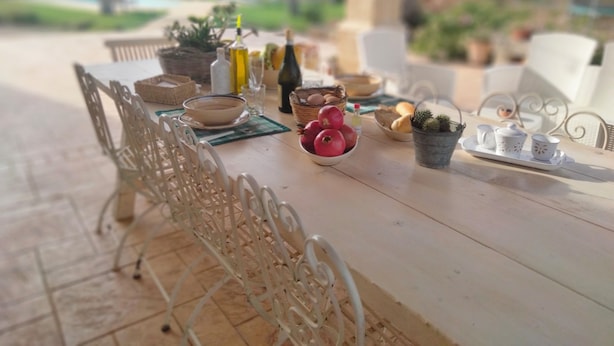 A dining table set with various items including a bowl of fruit, a small potted plant, and a tray with cups and saucers. - VILLA GINEVRA: typical Salento pajara with swimming pool in the Salento countryside. (Montesano Salentino)