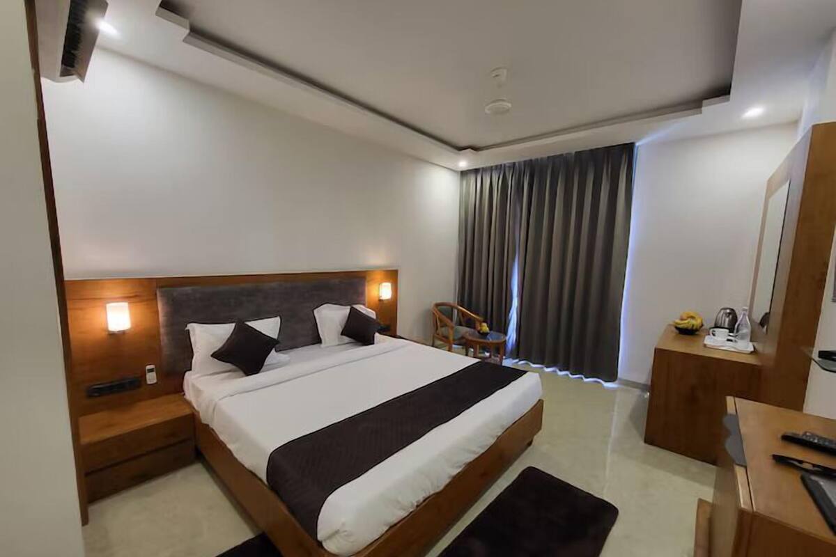 Una camera d'albergo moderna con un letto grande, una testiera in legno, comodini, una scrivania e una sedia.