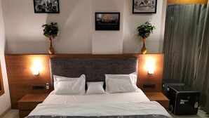 Une chambre d’hôtel avec un grand lit, deux tables de chevet, une tête de lit et des lampes fixées au mur.