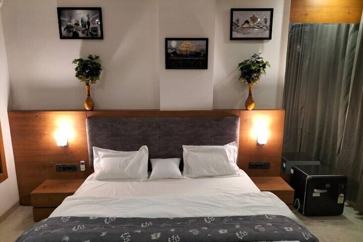 Camera d'albergo con un letto grande, due comodini, una testiera e luci a parete.