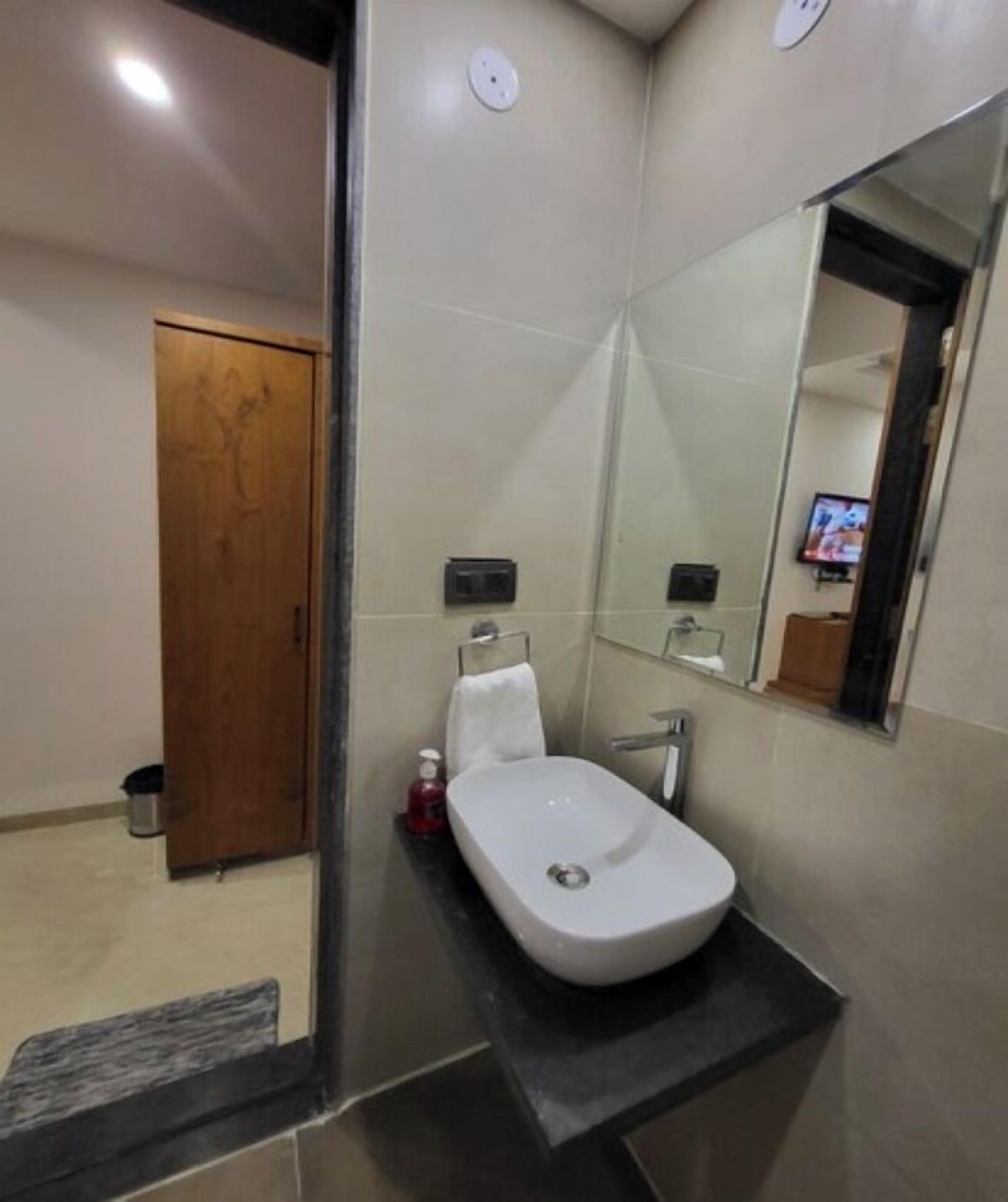 Une salle de bain moderne avec un lavabo blanc, un miroir et une porte en bois.