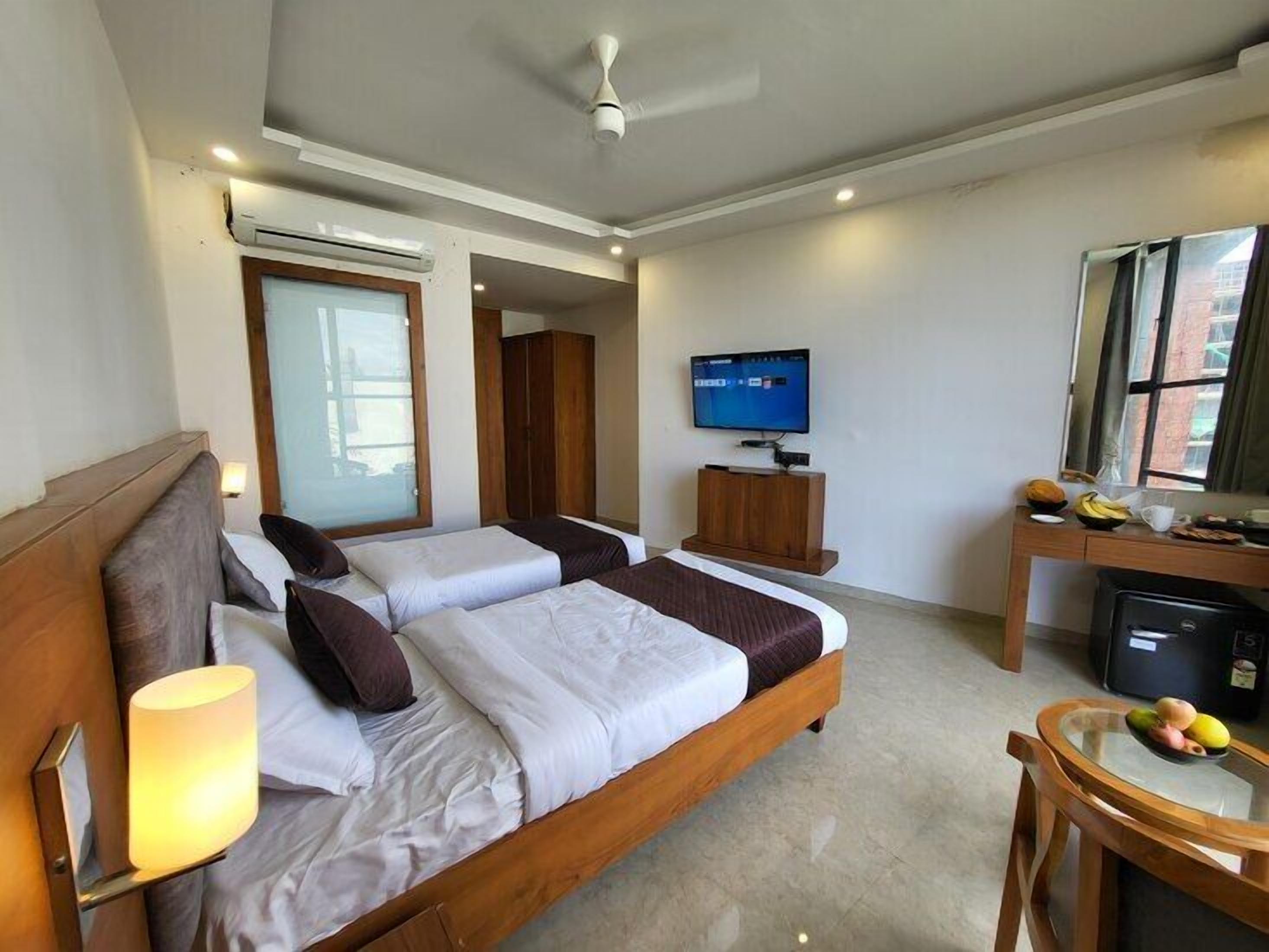 A hotel room with a large bed, a TV, a desk with a computer, and a window with a view.