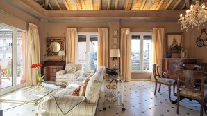 A spacious living room with a high ceiling, large windows, a chandelier, and a dining area with wooden furniture. - Villa Castro (Granada)