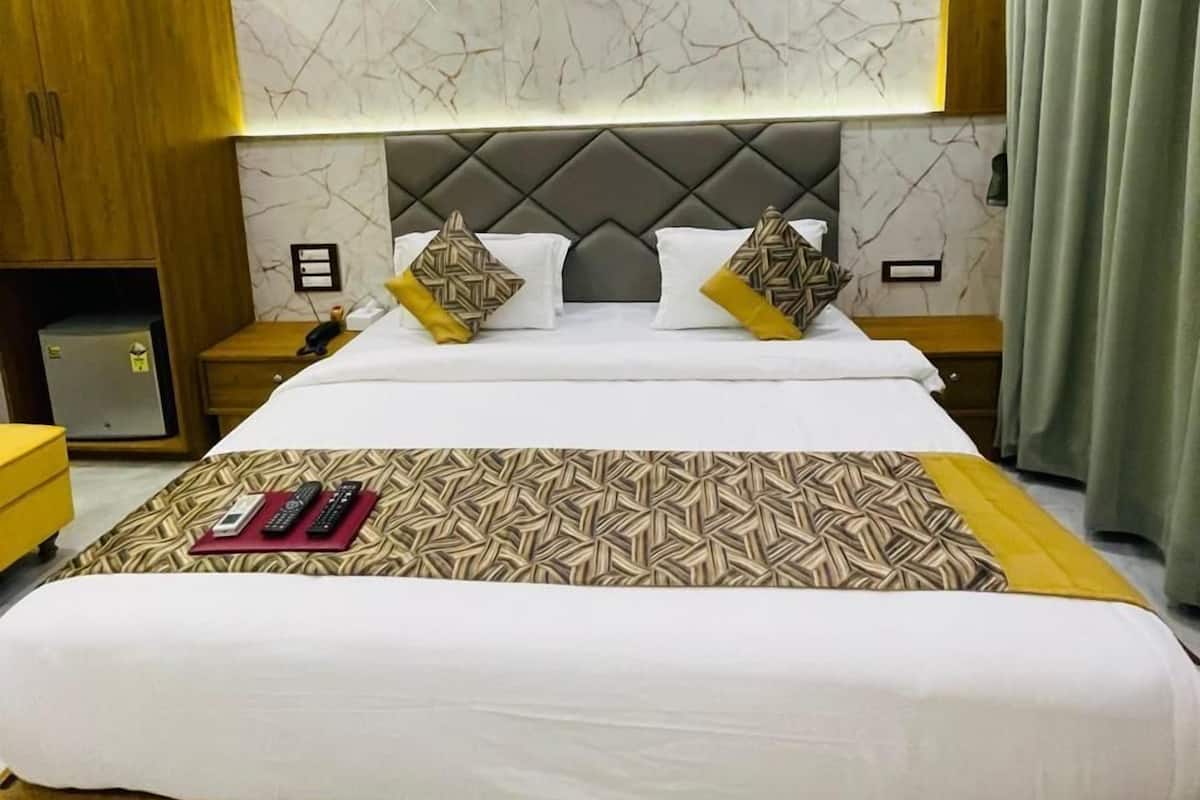 A modern hotel room with a large bed, marble-patterned headboard, and a wooden wardrobe.