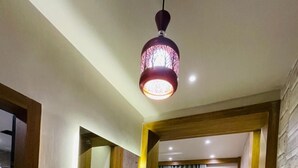 Ein modernes Hotelzimmer mit einer Holzbank, einem Schminktisch mit Spiegel, einem gelben Sessel und einem Marmorboden.