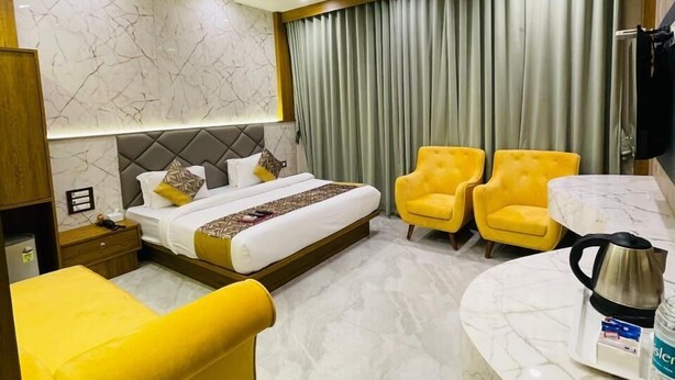 Ein Hotelzimmer mit einem Bett, einem Schreibtisch, zwei gelben Sessel, einem Marmorboden und einem Vorhang.