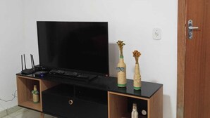 Eine schwarze TV-Konsole mit einem Flachbildfernseher, zwei dekorativen Vasen und einer Holztür.