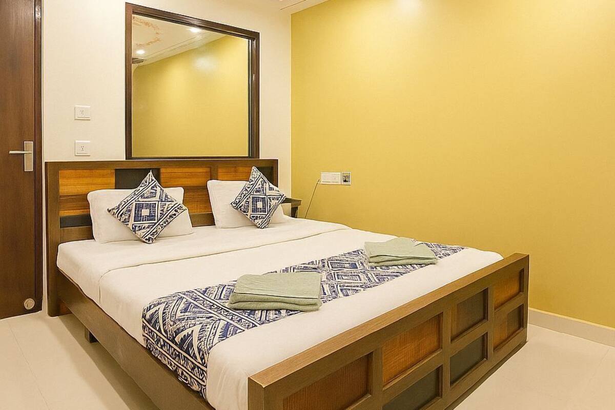 A bedroom with a bed, a ceiling fan, a mirror, and a door.