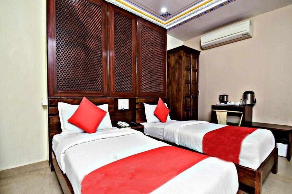 A hotel room with two beds, wooden headboards, and a desk with a chair.