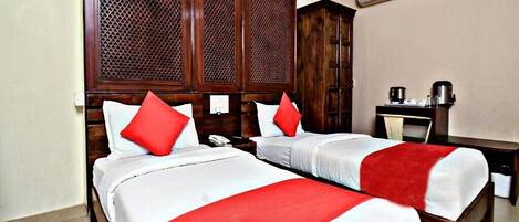 Habitación de hotel con dos camas, cabeceros de madera y un escritorio con silla.