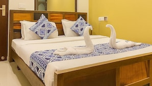 A hotel room with a wooden bed, white bedding, and decorative swan pillows. - The Umed (Jodhpur)