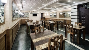 A spacious dining area with wooden tables and chairs, a patterned ceiling, and a modern design. - The Umed (Jodhpur)