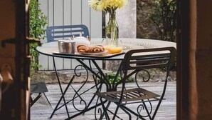 A patio with a round table, two chairs, a vase with flowers, and a basket of bread. - Le Clos du Maraicher Villandry (Villandry)