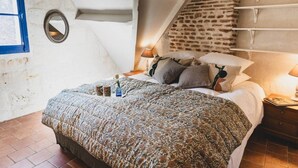 A bedroom with a bed, bedside tables, a mirror, and a brick wall. - Le Clos du Maraicher Villandry (Villandry)