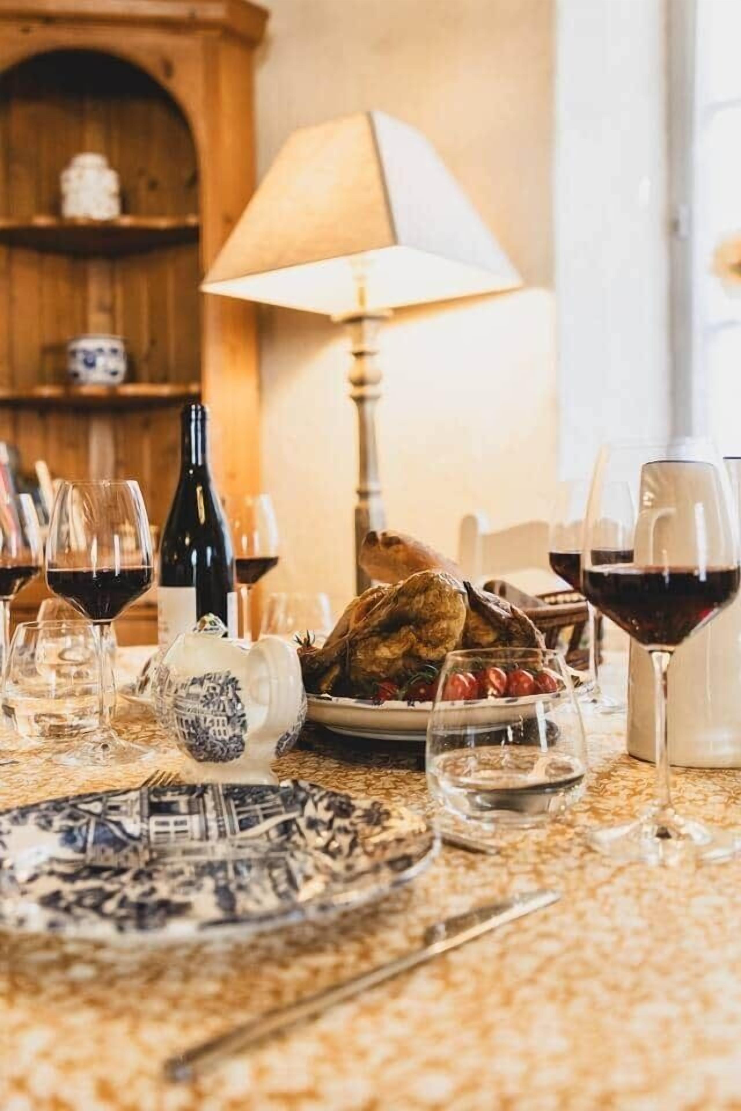 A dining table set with a roasted turkey, wine glasses, and plates.