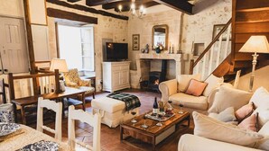 A cozy living room with a fireplace, a television, and a dining area with a table and chairs. - Le Clos du Maraicher Villandry (Villandry)