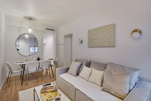 Ein modernes Wohnzimmer mit Essbereich, einer Couch und einem großen Spiegel.