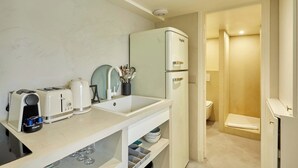 A compact kitchenette with a refrigerator, two toasters, a kettle, and a sink. - Chic Duplex with AC • Bastille & Marais (Paris)