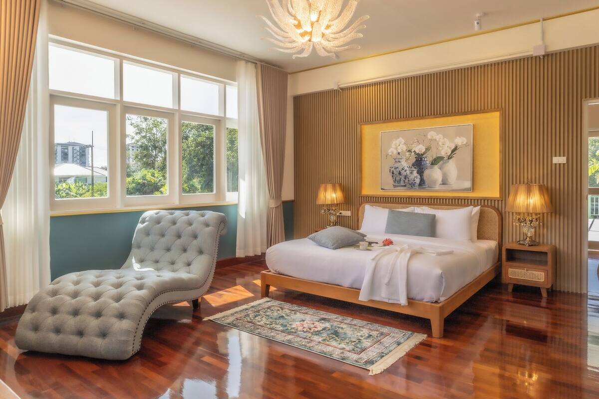 Una camera da letto con un letto grande, una poltrona imbottita e vista sul verde.