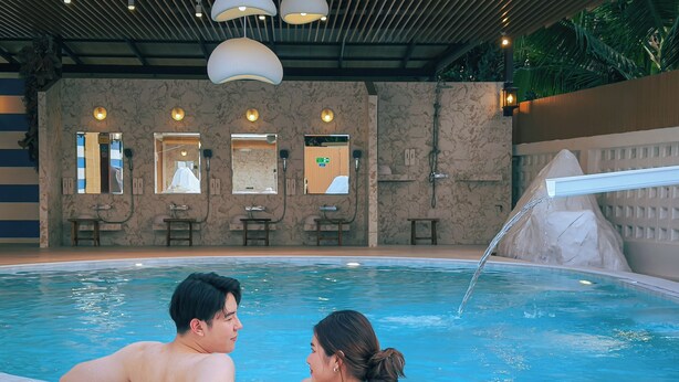 A couple relaxing by a pool with a spa area in the background. - Chez Nij Ryokan Onsen (Chiang Mai)