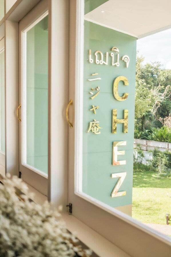 Una ventana con una pared verde y un letrero con letras doradas que dice 'CHEZ'.