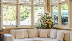 A living room with a sectional sofa, a coffee table, a chandelier, and decorative window panels. - Chez Nij Ryokan Onsen (Chiang Mai)