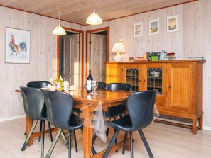 A dining area with a wooden table, black chairs, a wine bottle, and a lamp. - 4 Star Holiday Home in Oksbol (Oksbol)