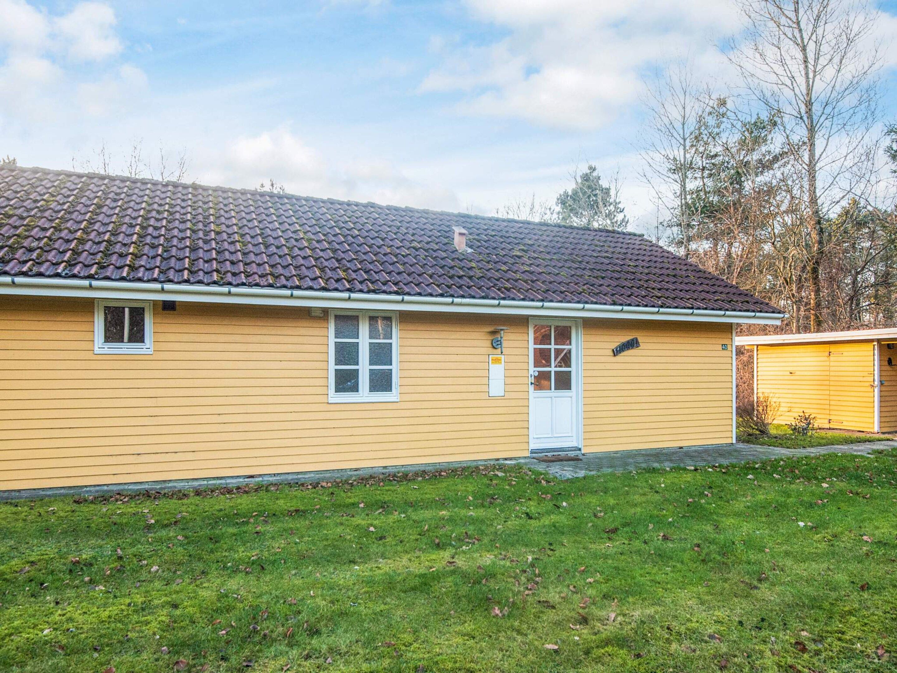 A single-story yellow building with a tiled roof, a front door, and a small window.