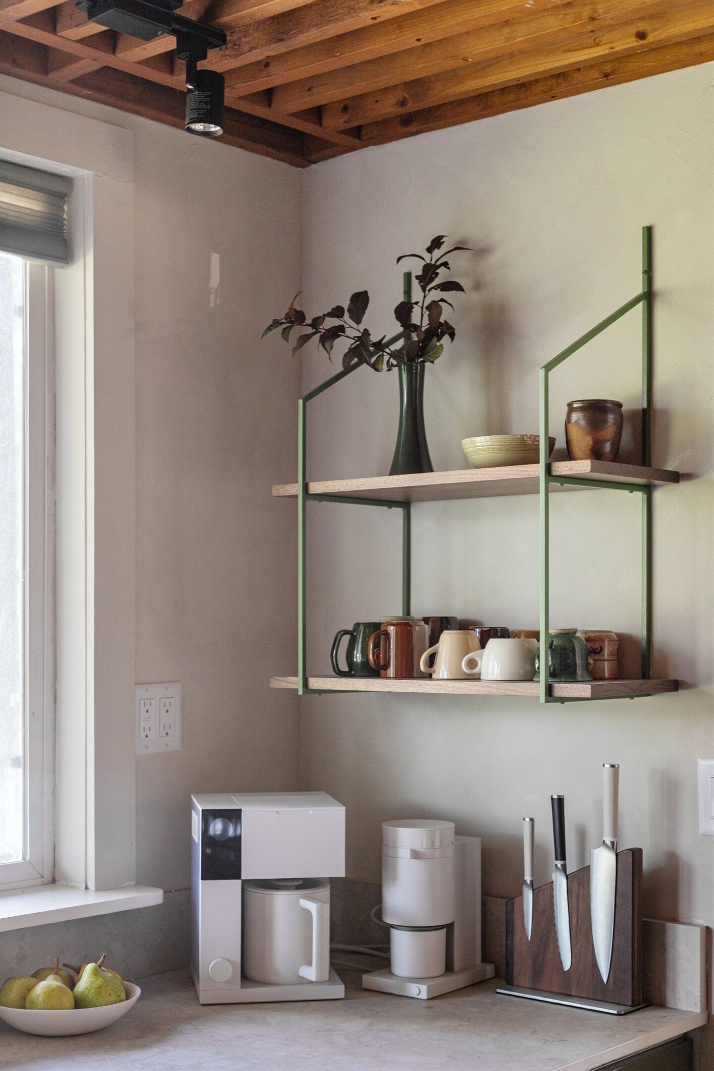 A kitchen with a coffee maker, a fruit bowl, and a knife block.
