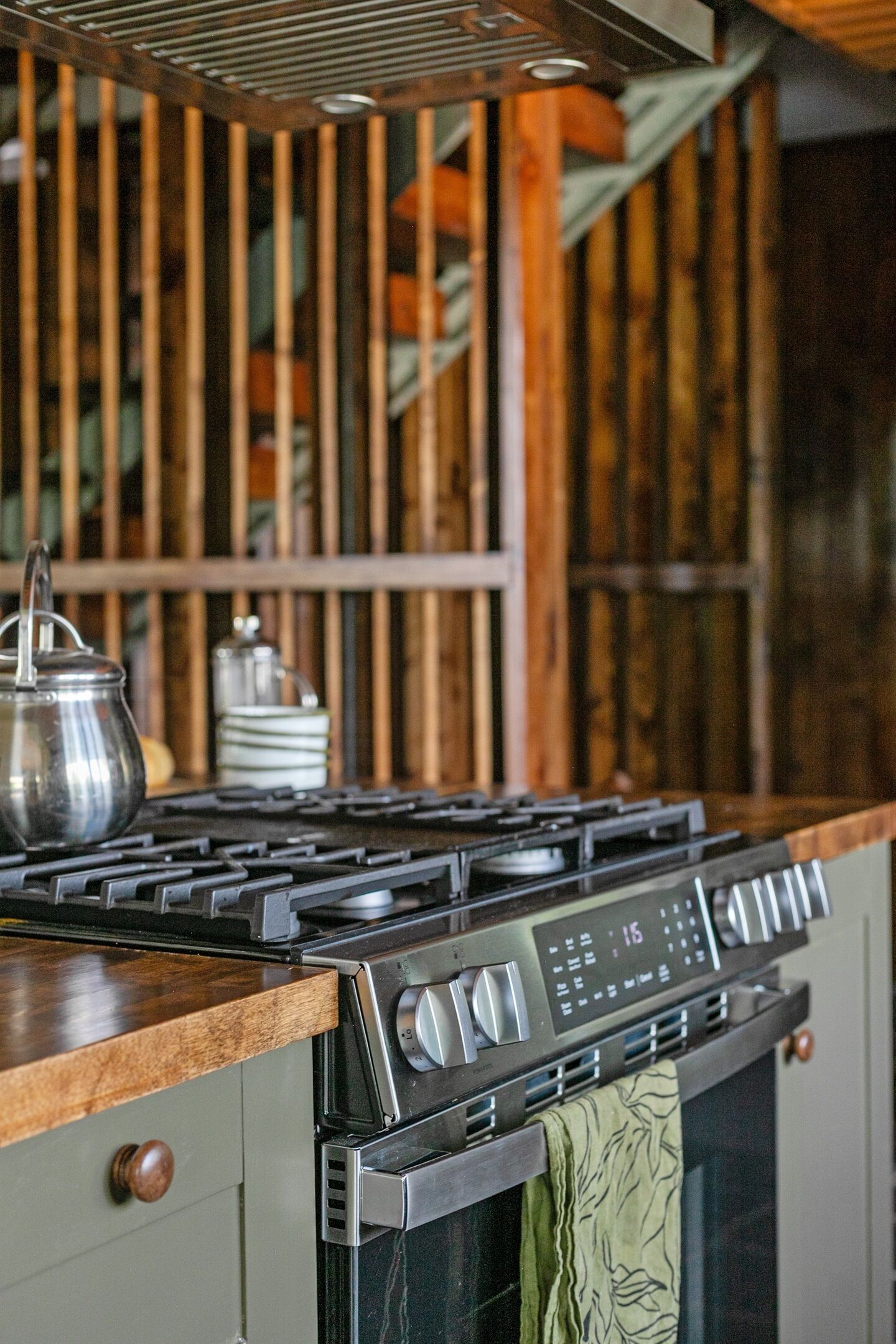 Une cuisine équipée d’une cuisinière à gaz, d’un four et d’un mur en bois.
