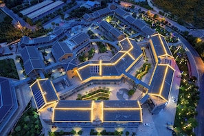 An aerial view of a complex with interconnected buildings, featuring a central courtyard and multiple parking areas. - Yi Jia Hotel (Kunming)