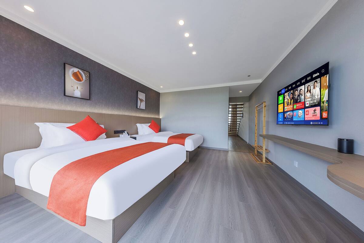 A hotel room with a large bed, a TV mounted on the wall, and a wooden floor.