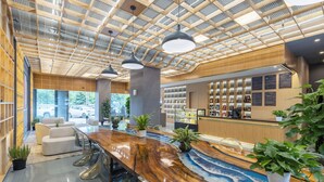 A modern hotel lobby with a wooden reception desk, clear glass chairs, and a ceiling with a geometric pattern. - Yi Jia Hotel (Kunming)
