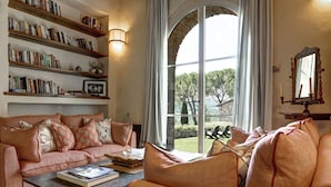 Ein gemütliches Wohnzimmer mit einer Couch, einem Couchtisch mit Büchern und einem Bücherregal, voll mit Büchern.