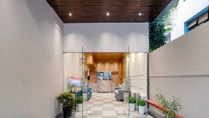 A hotel lobby with a checkered floor, seating area, reception desk, and a glass partition. - Palette Hotel Pune, Midc Chinchwad (Pune)