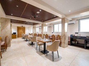 A modern dining area with marble flooring, wooden ceiling panels, and a mix of wooden and upholstered chairs. - Palette Hotel Pune, Midc Chinchwad (Pune)