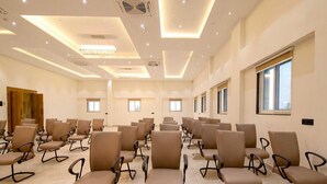 A spacious conference room with rows of chairs, ceiling lights, and windows. - Palette Hotel Pune, Midc Chinchwad (Pune)