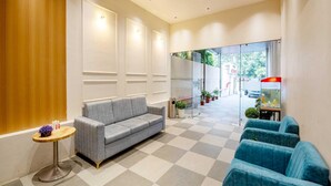 A reception area with a grey sofa, a small round table, and a blue seating area. - Palette Hotel Pune, Midc Chinchwad (Pune)