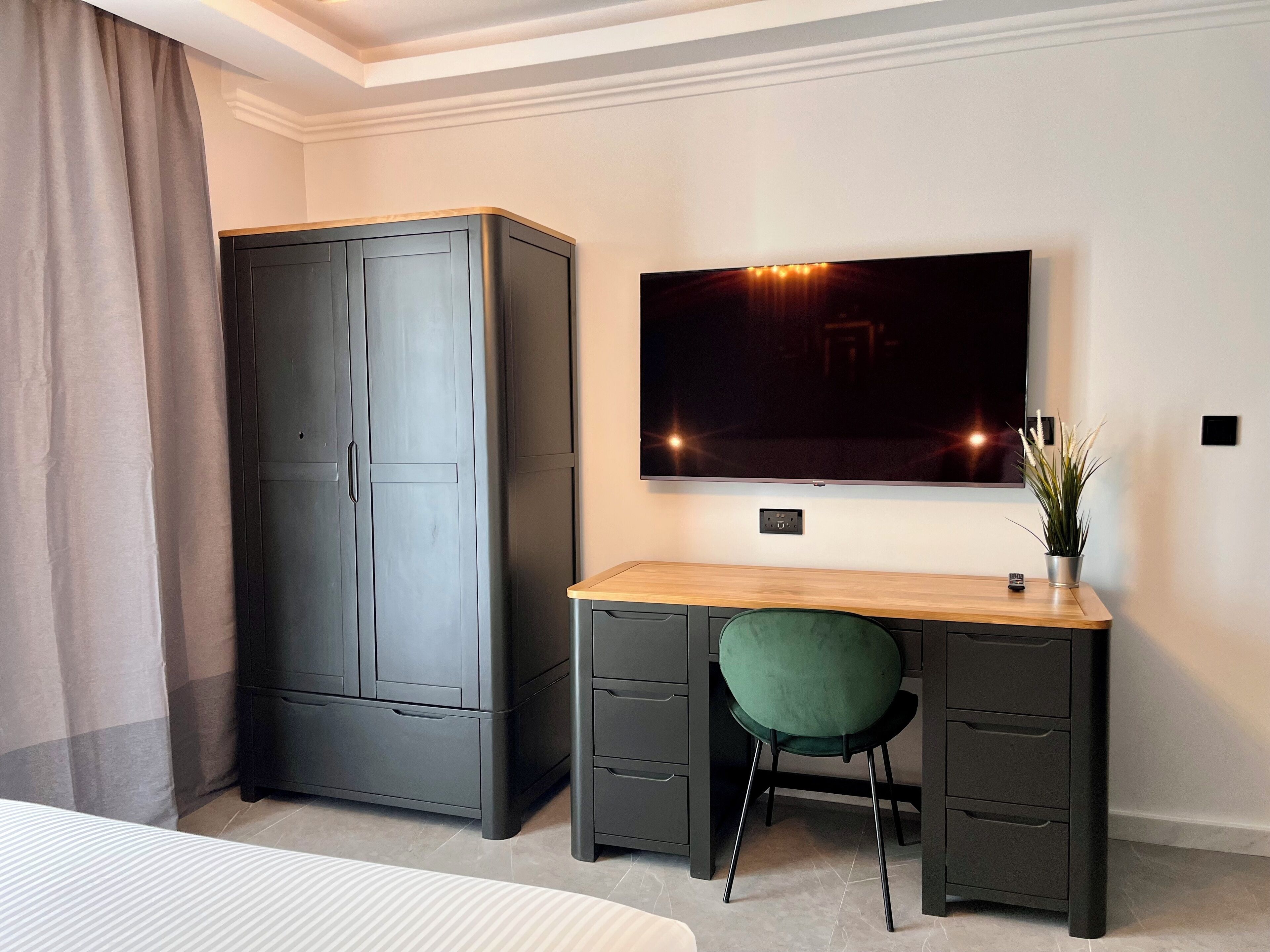 Une chambre d’hôtel comprenant un lit, un bureau avec une chaise, une télévision et une armoire.