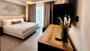 A modern hotel room with a large bed, a wooden desk, a television mounted on the wall, and a decorative wall piece. - Sliema Studios (Sliema)
