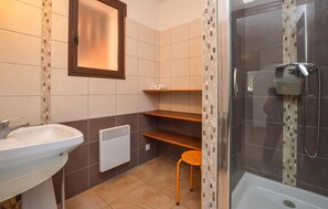 Ein Badezimmer mit Waschbecken, Spiegel, Handtuchhalter, Dusche und Heizkörper.