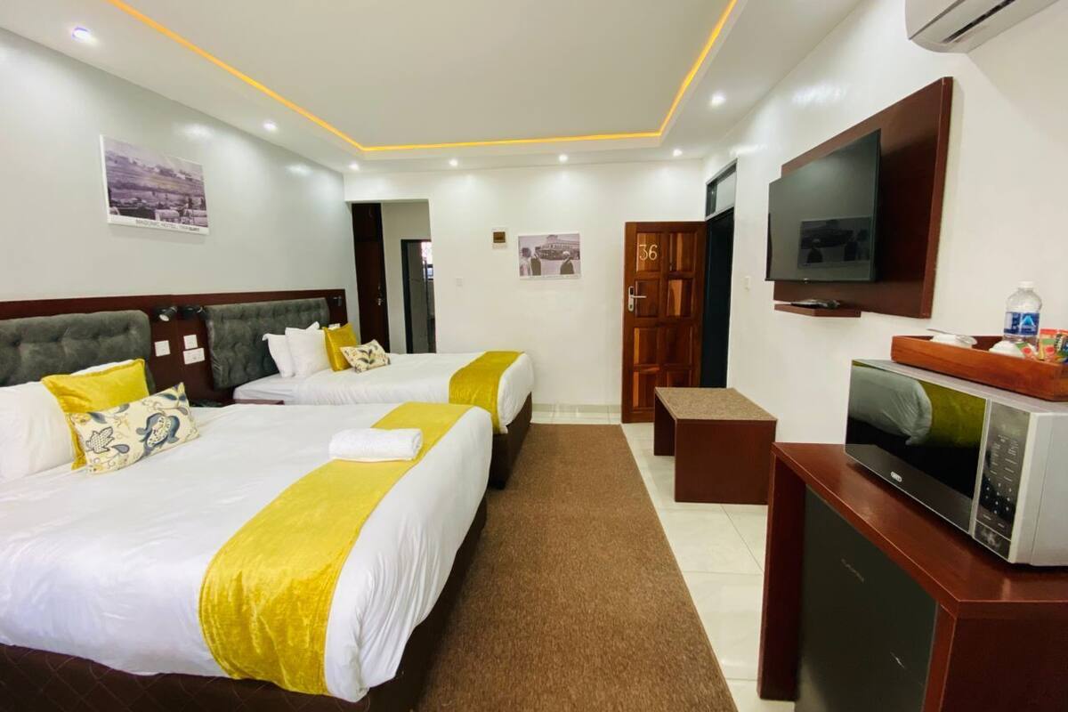 A hotel room with two beds, a TV, a microwave, and a small desk.