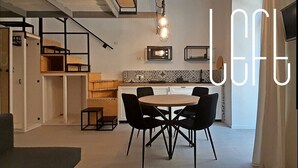 Eine moderne Küche mit Essbereich, ausgestattet mit einem runden Tisch und schwarzen Stühlen, einer Pendelleuchte und einer gemusterten Spritzschutzwand.