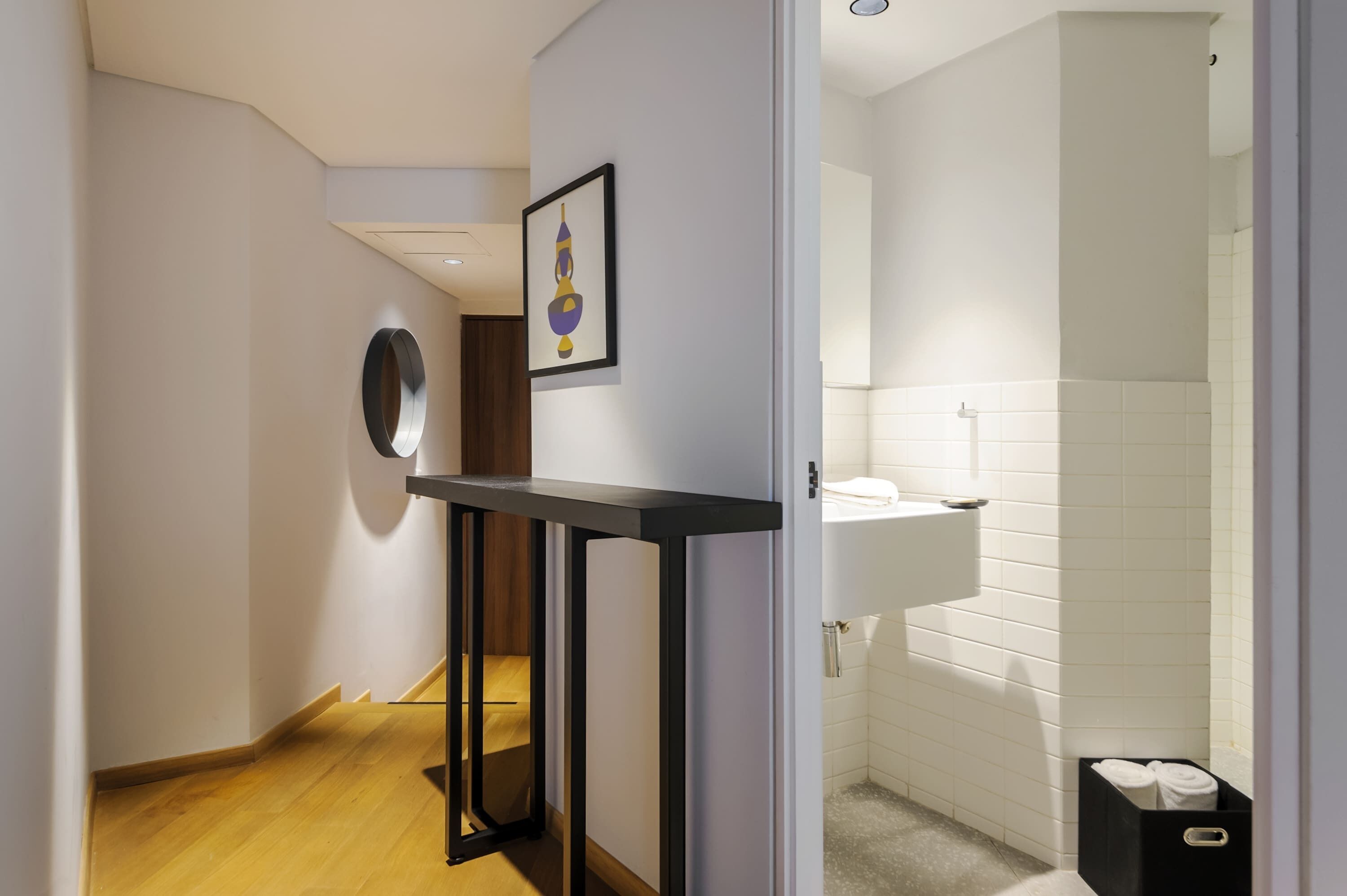 Un baño moderno con un lavamanos blanco, un espejo y una obra de arte enmarcada en la pared.