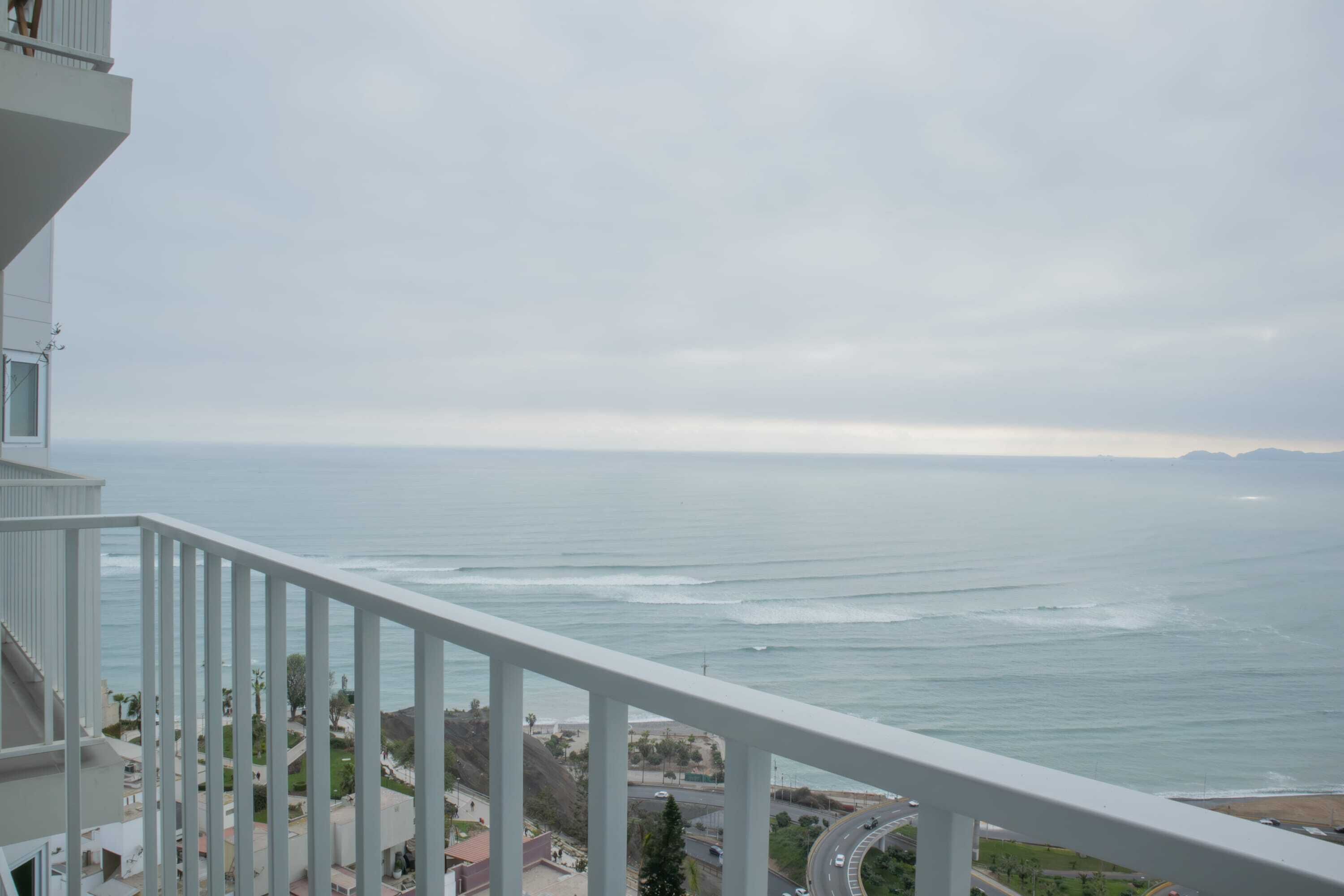 A balcony with a view of the ocean and a road.