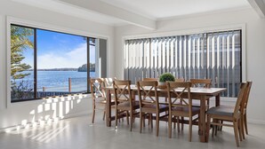 Uma sala de jantar com vista para o mar, janelas amplas e design de interiores moderno.