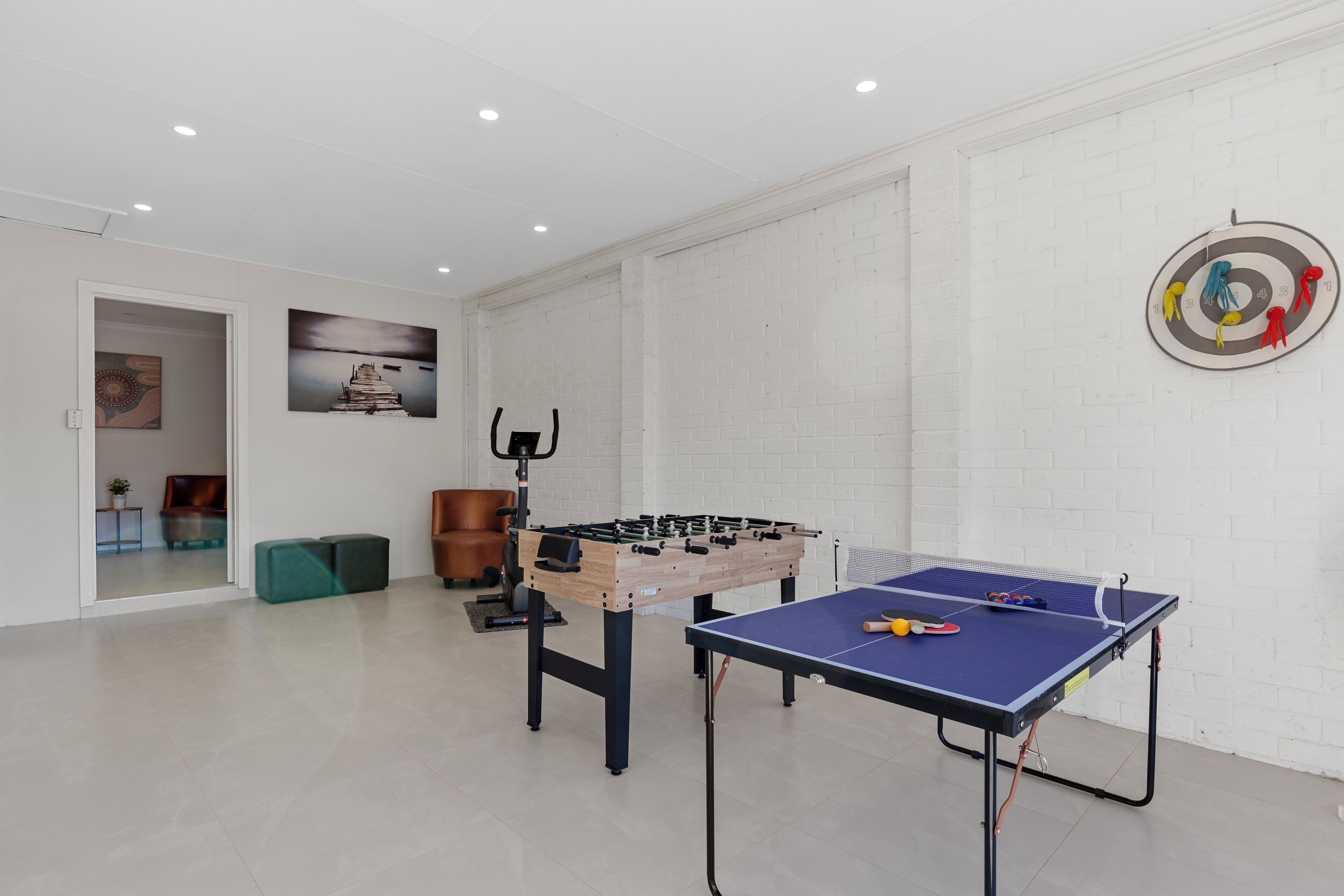 Une pièce équipée d’un baby-foot, d’une table de ping-pong et d’un jeu de fléchettes au mur.