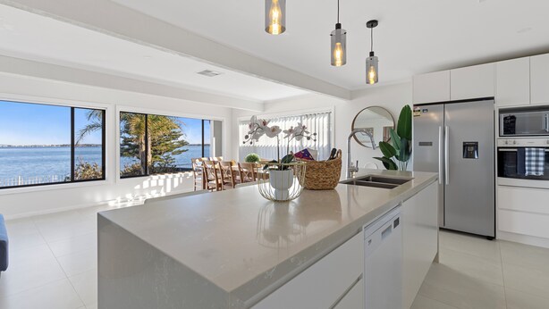 Cozinha moderna com uma ilha grande, eletrodomésticos de aço inoxidável e vista para o mar.