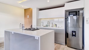 A modern kitchen with a central island, stainless steel appliances, and a built-in oven. - w* | Radiant 2BR w/ Balcony in Santa Barbara (Bogotá)