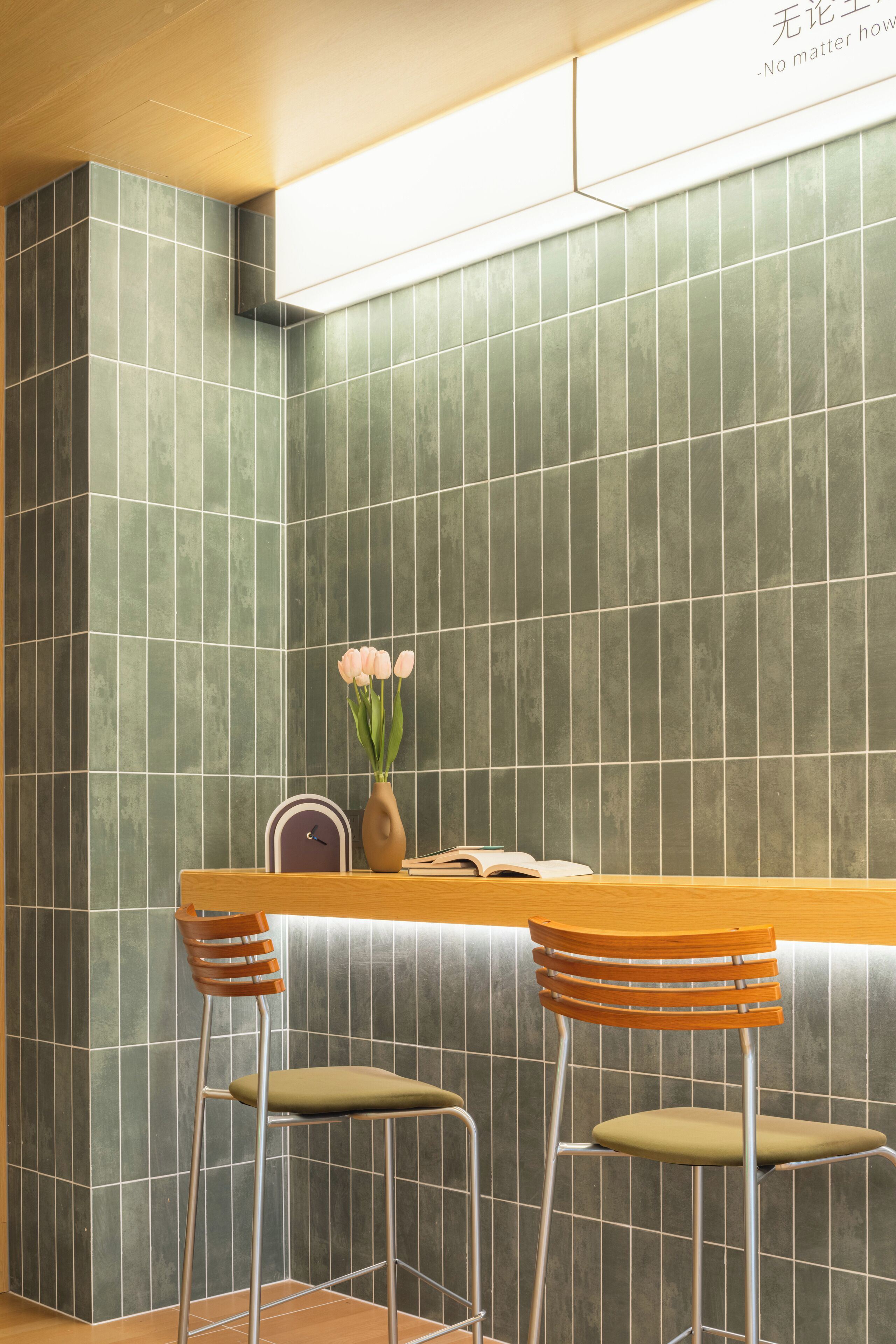 A modern interior with a wooden table and two chairs, a vase with flowers, and a clock on the wall.
